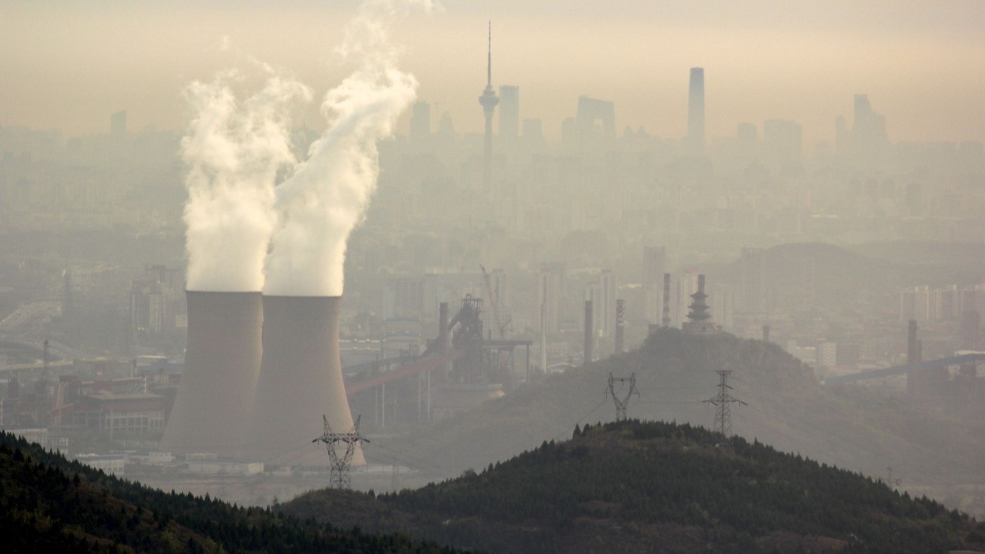 Aerial view over coal-fired power station, through haze of emissions smog