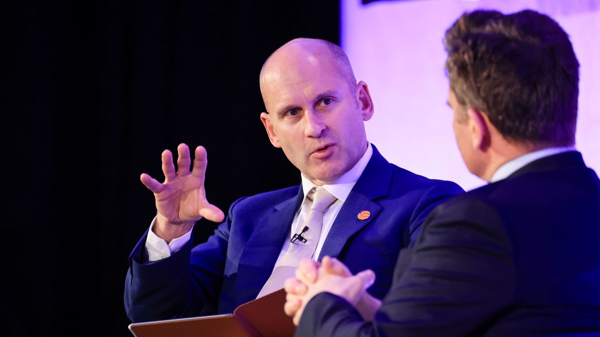 Close up of Nick Wayth (left of photo) talking to an energy executive (right) with his back to the camera, both are seated; Nick has right hand raise to emphasis a point being made