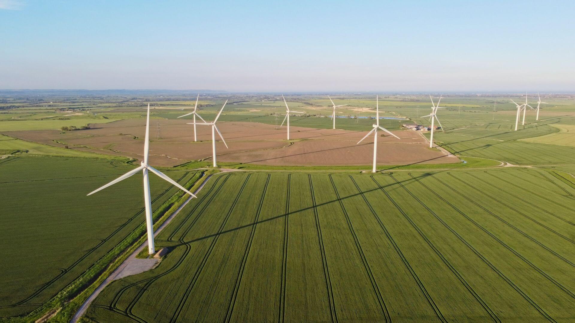 Aerial view over onshore wind farm set in flat green fields